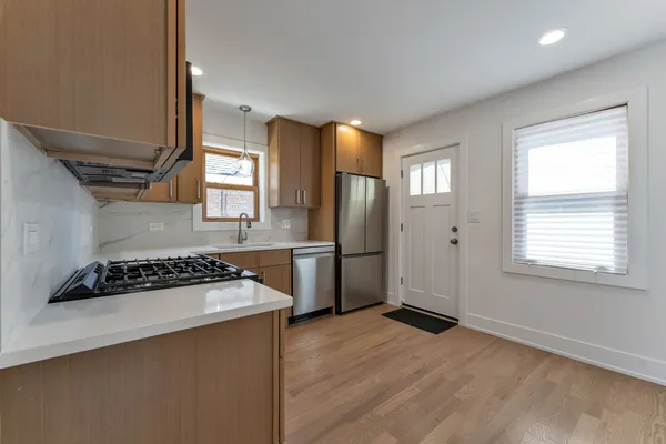a kitchen with stainless steel appliances a stove a refrigerator a sink a refrigerator wooden floor and cabinets