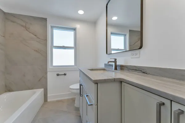 a bathroom with a granite countertop sink a toilet and a bathtub