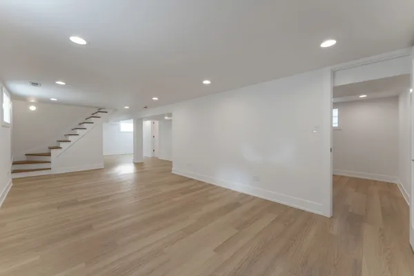 a view of an empty room with wooden floor and staircase
