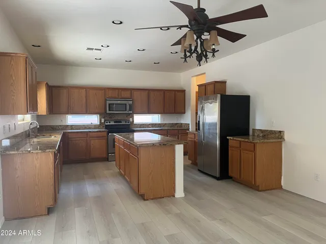 a kitchen with stainless steel appliances granite countertop a refrigerator a stove top oven a sink and dishwasher