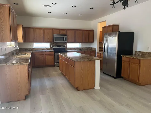 a kitchen with stainless steel appliances granite countertop a stove a sink and a refrigerator