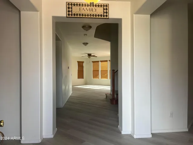 a view of a hallway with wooden floor and a living room
