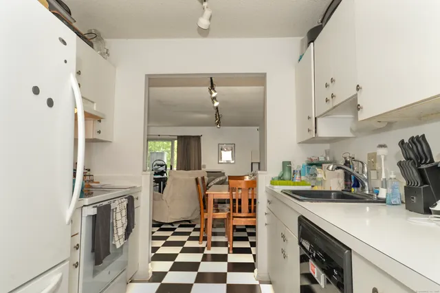 a kitchen with stainless steel appliances a refrigerator a sink a stove and white cabinets