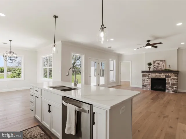a view of a livingroom with a fireplace a ceiling fan and wooden floor