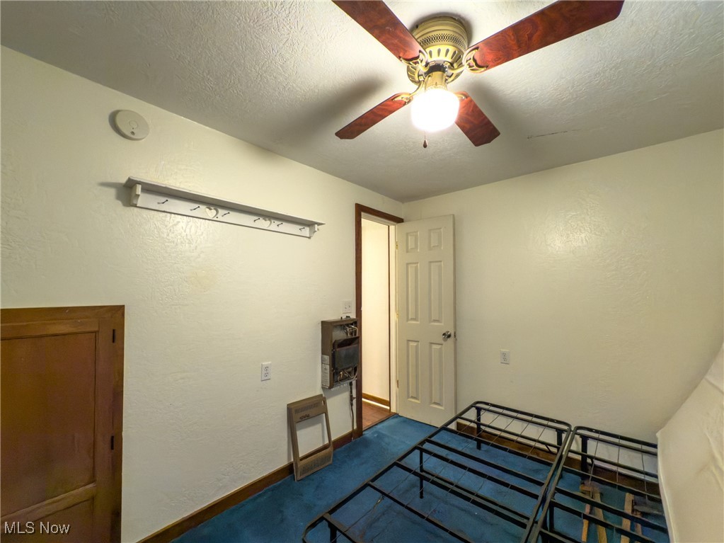 36475 Kinney Ridge Road Woodsfield, OH 43793 - Photo 26 of 50 Unfurnished bedroom with dark colored carpet, ceiling fan, a textured ceiling, and a textured wall