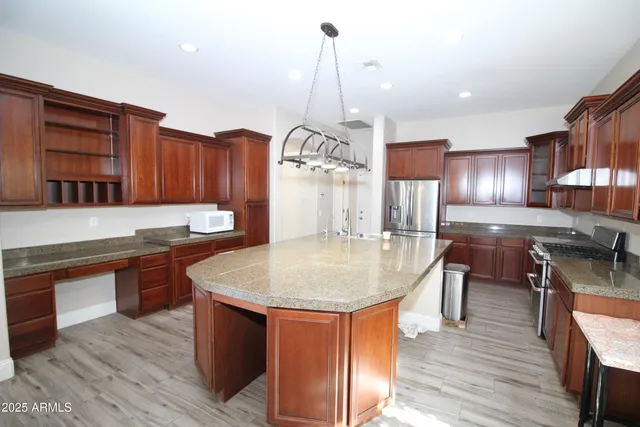 a kitchen with stainless steel appliances granite countertop a sink a kitchen island a stove and a wooden floors