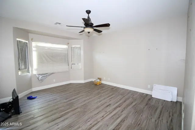 an empty room with wooden floor and windows