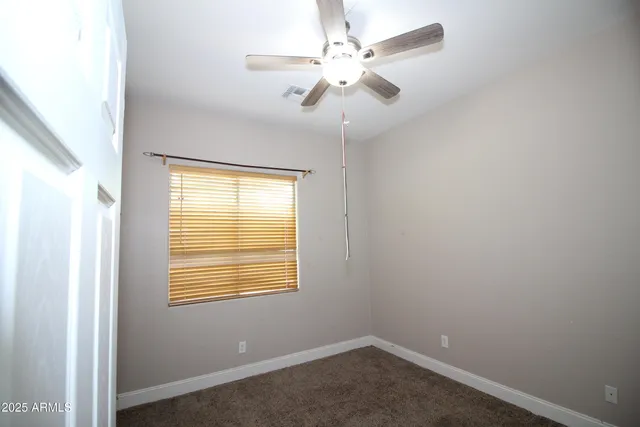 an empty room with a window and a fan