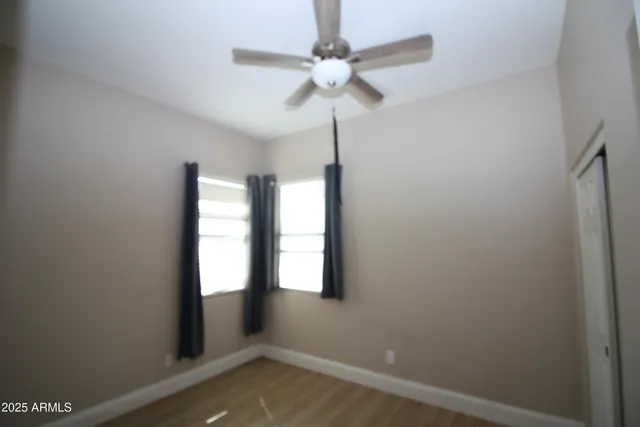 an empty room with windows and fan