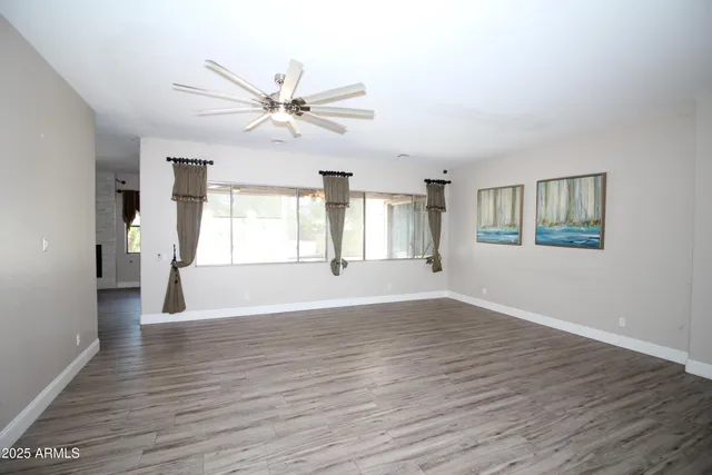 a view of an empty room with window and wooden floor