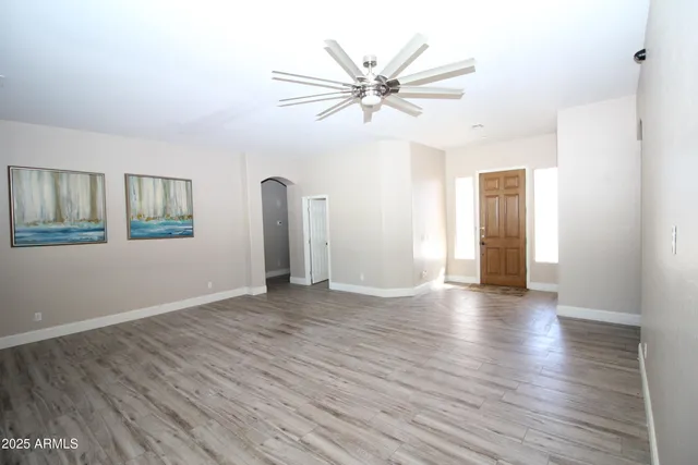 a view of an empty room with window and wooden floor
