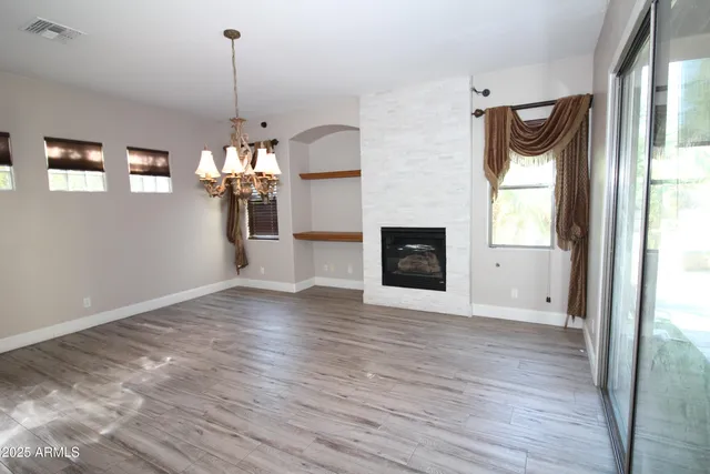 a view of an empty room with window and wooden floor