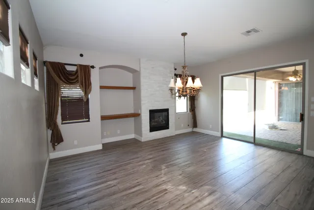 a view of a room with wooden floor fireplace and window