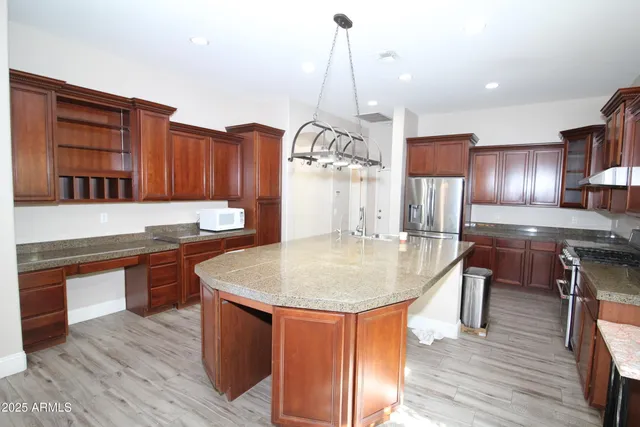 a kitchen with stainless steel appliances granite countertop a kitchen island a stove a sink and a wooden floors