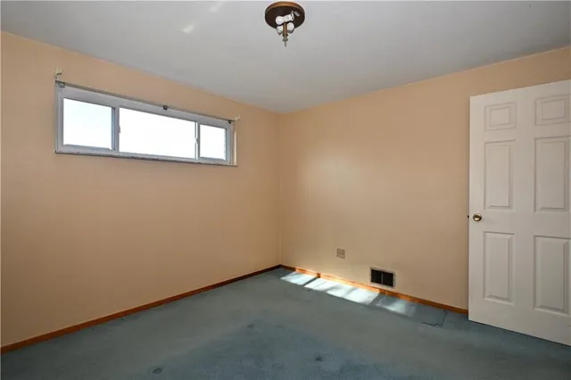 an empty room with ceiling fan and window
