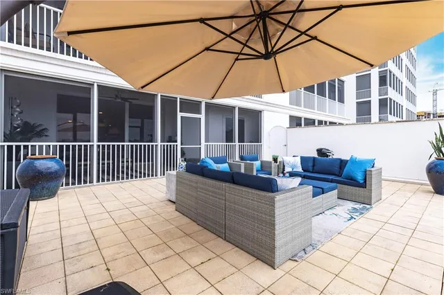 a view of a patio with couches and chairs under an umbrella