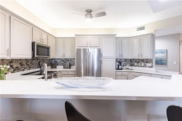a view of a kitchen with kitchen island a sink stainless steel appliances and cabinets