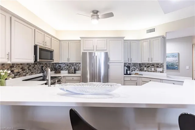 a view of a kitchen with kitchen island a sink stainless steel appliances and cabinets