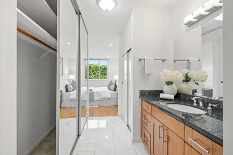 a bathroom with a granite countertop sink a mirror and a shower