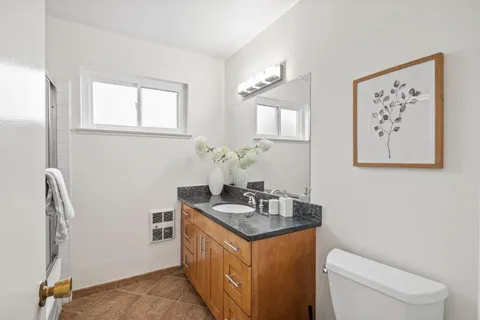 a bathroom with a granite countertop sink and a toilet