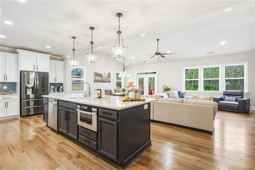 265 Fountain Oak Way Canton, GA 30114 - Photo 9 of 59 a large kitchen with stainless steel appliances kitchen island granite countertop a large kitchen island a stove a refrigerator a sink dishwasher and a fireplace with wooden floor
