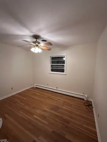 a view of an empty room with wooden floor and chandelier