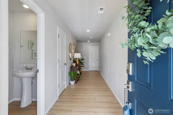 a hallway with wooden floor and a potted plant