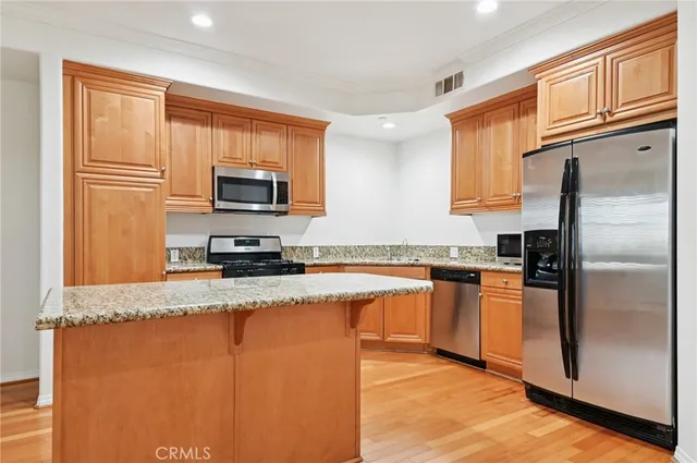 a kitchen with granite countertop a refrigerator stove top oven and sink