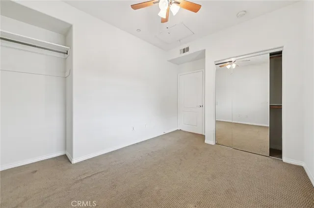 an empty room with a chandelier fan and closet area