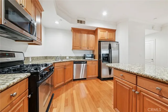 a kitchen with granite countertop a stove top oven microwave and refrigerator