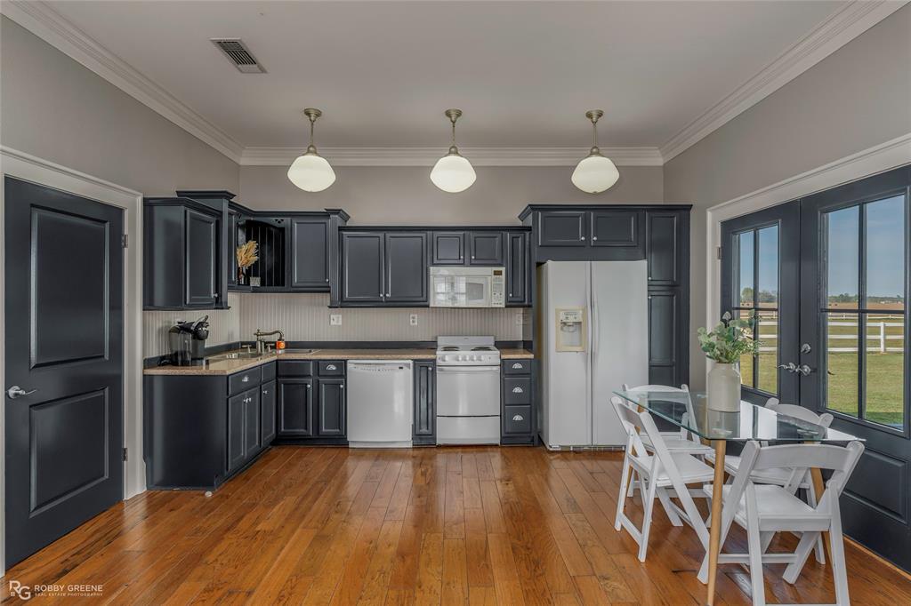 8265 Cornhusker Road Shreveport, LA 71107 - Photo 35 of 39 a kitchen with stainless steel appliances granite countertop a refrigerator a stove top oven a sink dishwasher a dining table and chairs with wooden floor