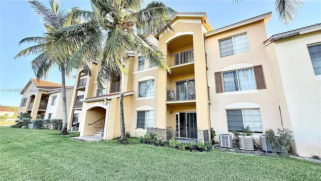 a view of a white house with a yard and potted plants