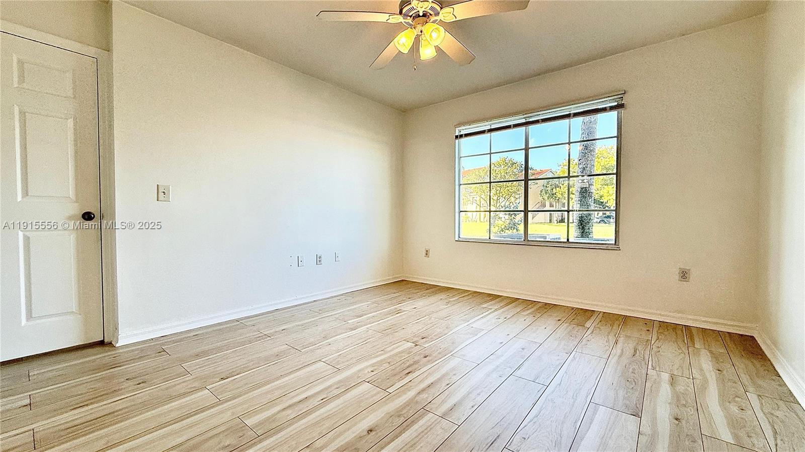 4190 San Marino Boulevard, Unit 102 West Palm Beach, FL 33409 - Photo 20 of 33 an empty room with wooden floor chandelier fan and windows