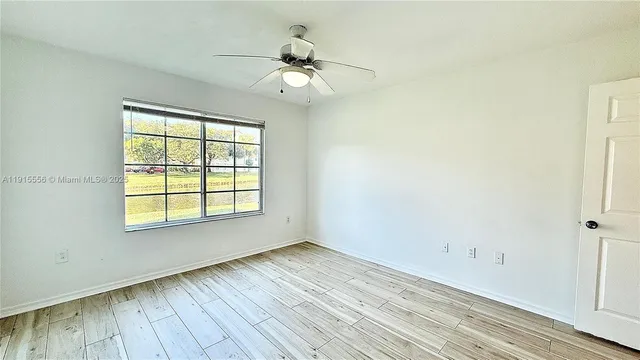 a view of a room with wooden floor and a ceiling fan