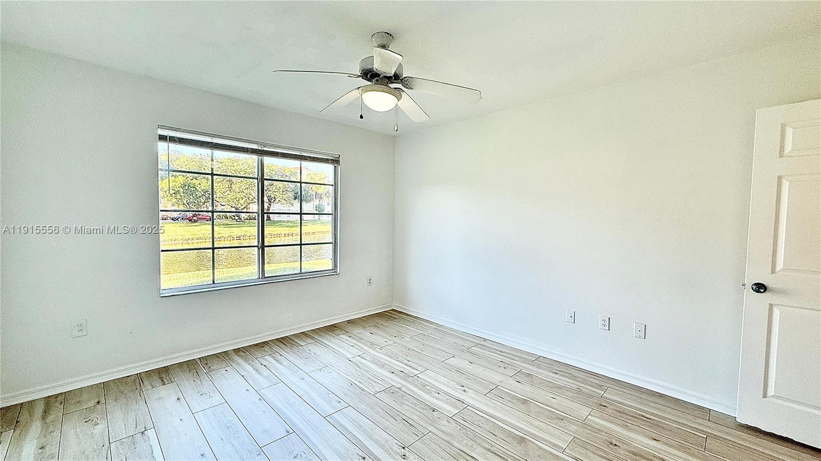 4190 San Marino Boulevard, Unit 102 West Palm Beach, FL 33409 - Photo 28 of 33 an empty room with wooden floor fan and windows