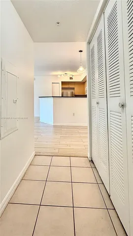 a view of a refrigerator and an empty room with wooden floor