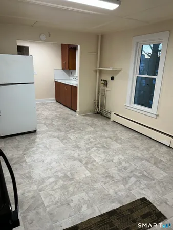 a view of a refrigerator in kitchen and an empty room