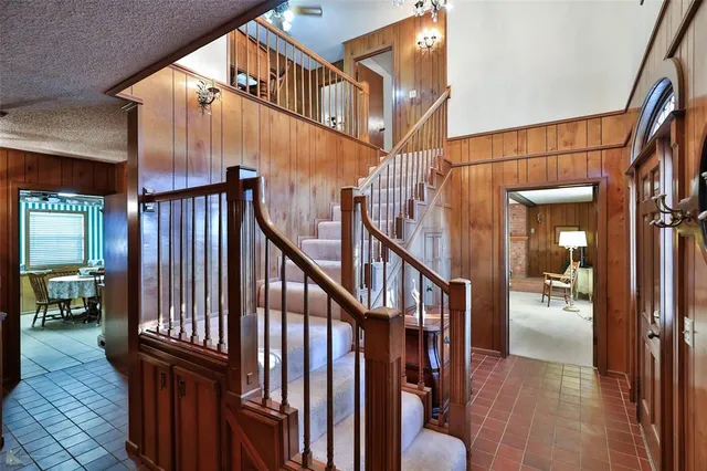 a view of staircase with lots of frames on wall and a chandelier