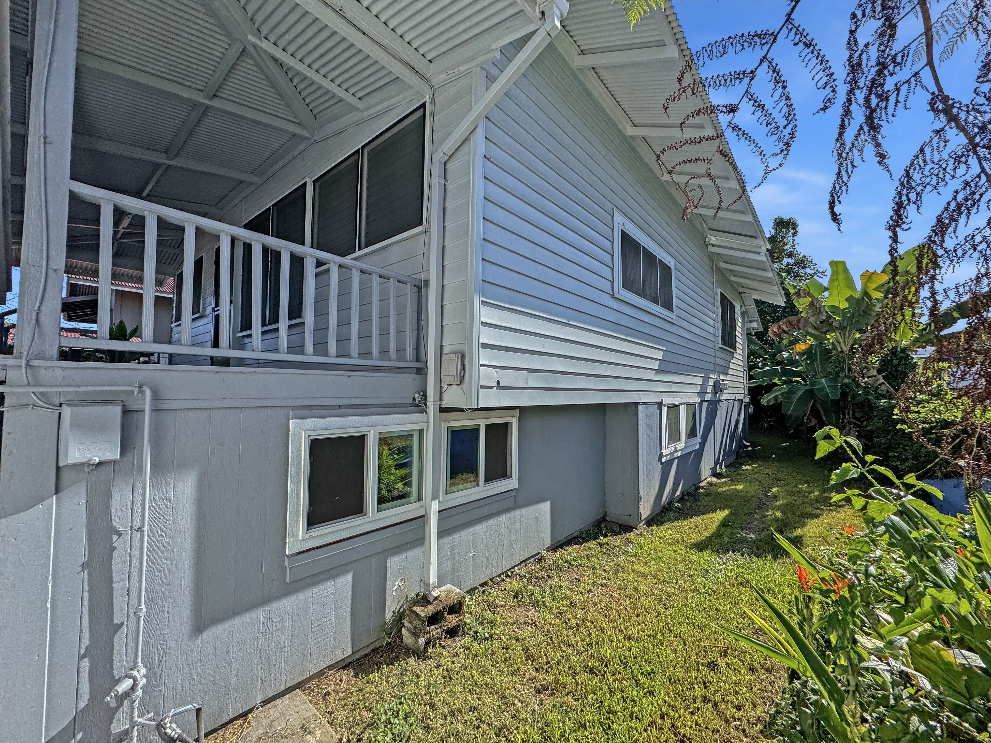 136 Mauna Loa Street Hilo, HI 96720 - Photo 22 of 23 a view of house with large windows and flower plants