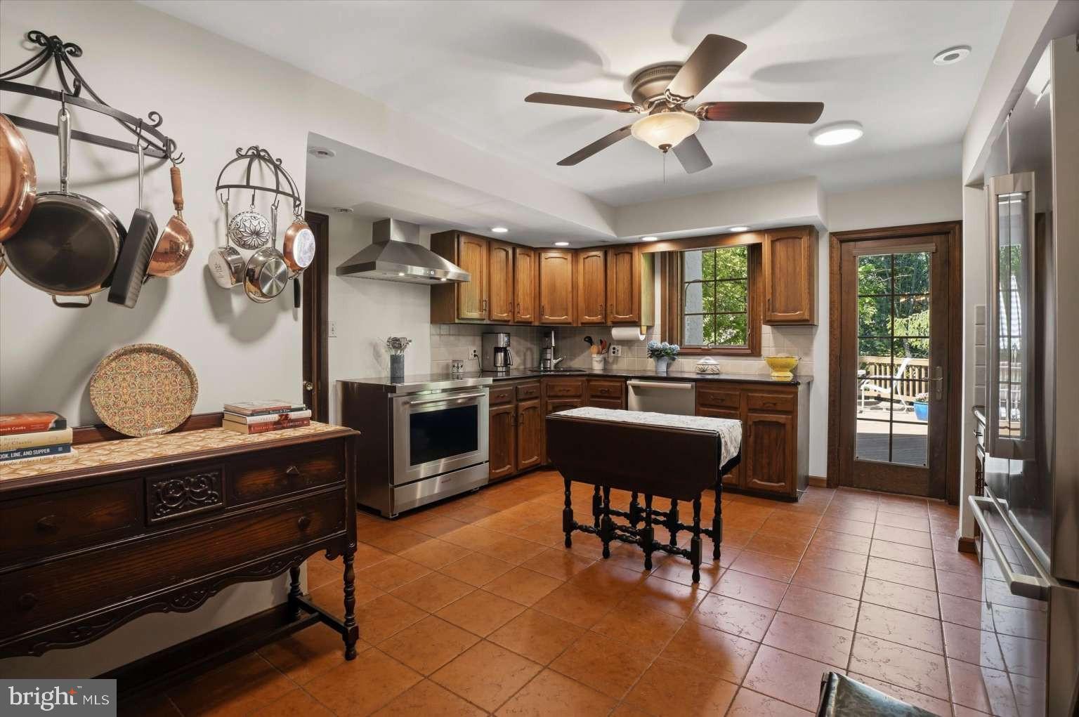 273 Strafford Avenue Wayne, PA 19087 - Photo 12 of 42 a kitchen with stainless steel appliances kitchen island granite countertop a stove a sink a dining table and chairs with wooden floor