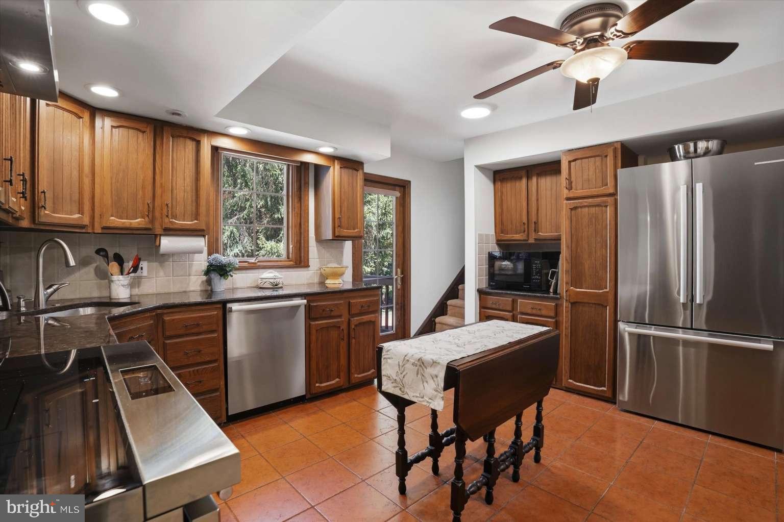 273 Strafford Avenue Wayne, PA 19087 - Photo 14 of 42 a kitchen with a refrigerator a sink dishwasher a stove and a dining table with wooden floor