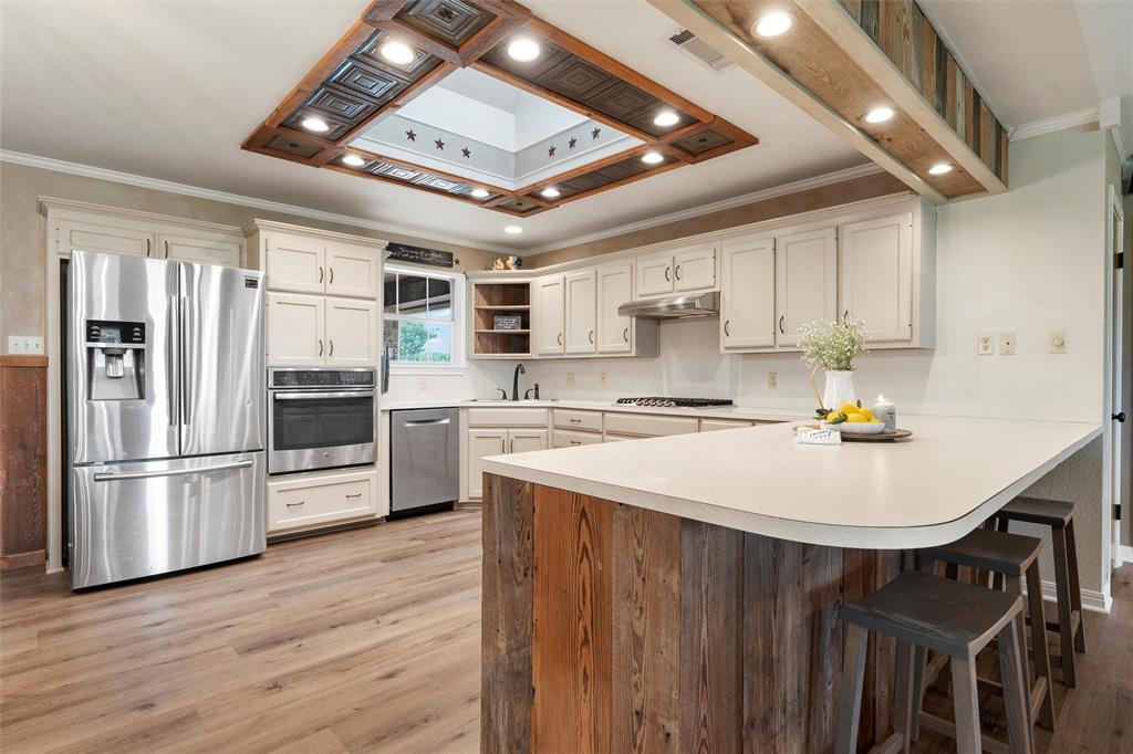 3057 Holy Road Abbott, TX 76621 - Photo 13 of 39 a kitchen with stainless steel appliances a stove a sink dishwasher a refrigerator with white cabinets and wooden floor