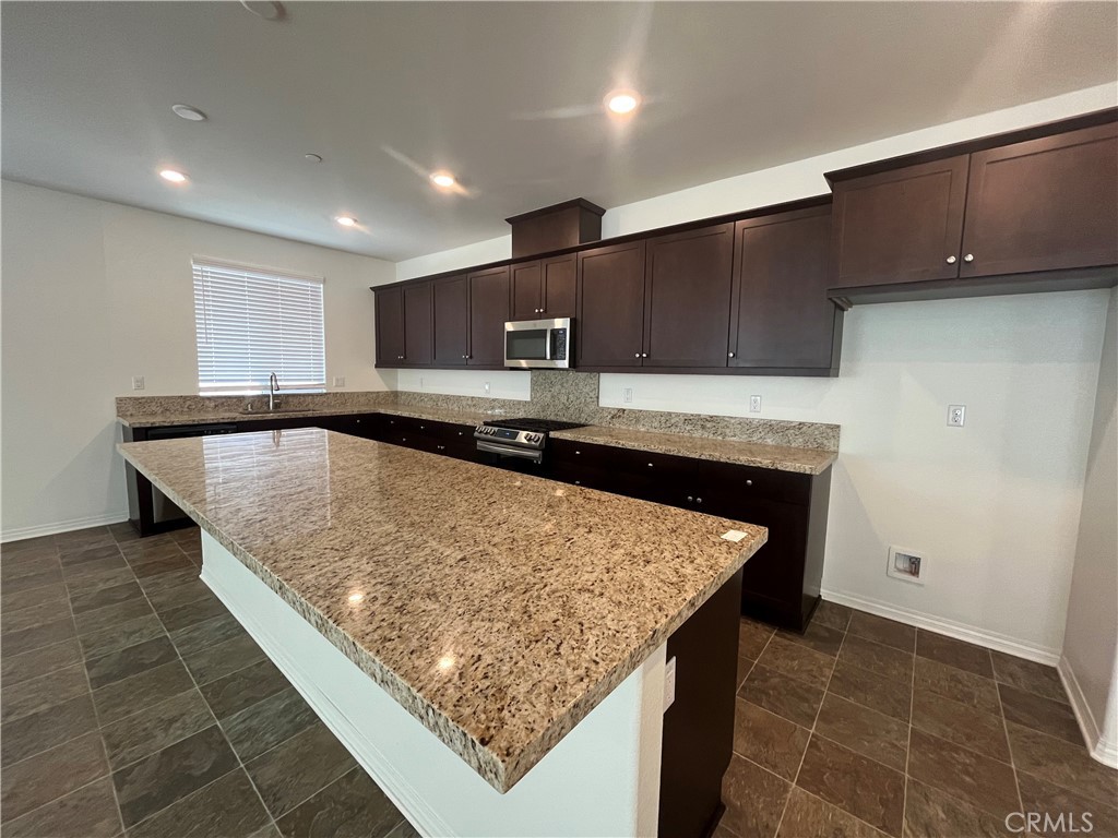 5233 Saloon Street Hemet, CA 92545 - Photo 12 of 18 a kitchen with kitchen island granite countertop wooden cabinets and granite counter tops