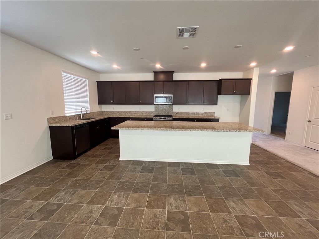 5233 Saloon Street Hemet, CA 92545 - Photo 13 of 18 a large kitchen with kitchen island a sink a counter top and stainless steel appliances