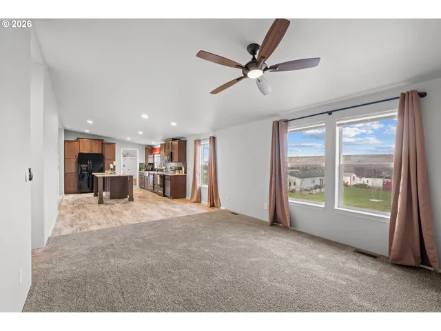 a view of a big room with windows and chandelier fan