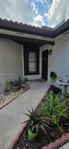 a front view of a house with a yard and potted plants