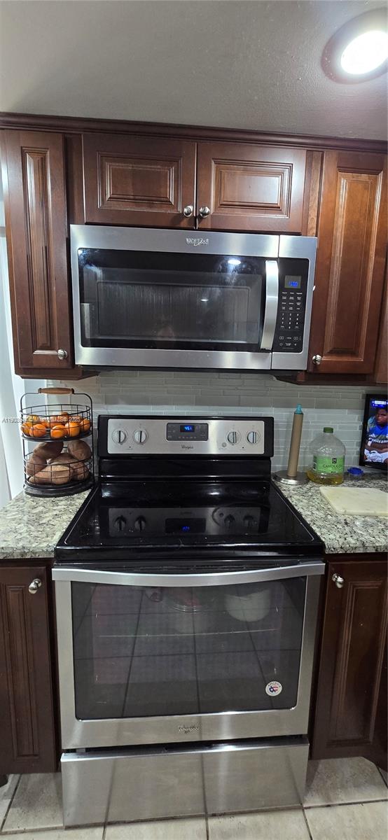 4860 Southwest 152nd Place, Unit F92 Miami, FL 33185 - Photo 5 of 6 a kitchen with granite countertop a stove and a microwave