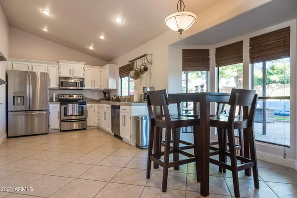 a kitchen with stainless steel appliances granite countertop a stove a refrigerator a kitchen island a table and chairs