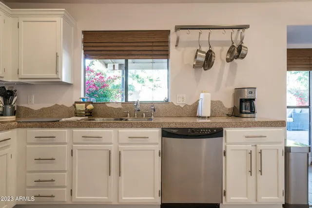 a kitchen with granite countertop white cabinets and window