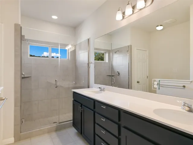 a bathroom with a double vanity sink mirror and shower